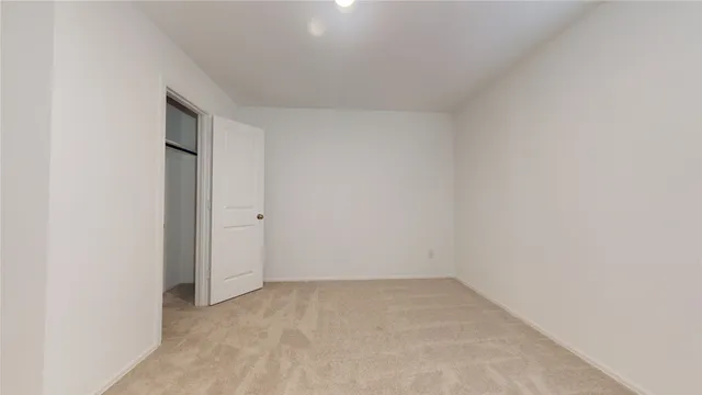 a view of an empty room with closet and a window