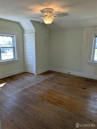 an empty room with wooden floor chandelier fan and windows