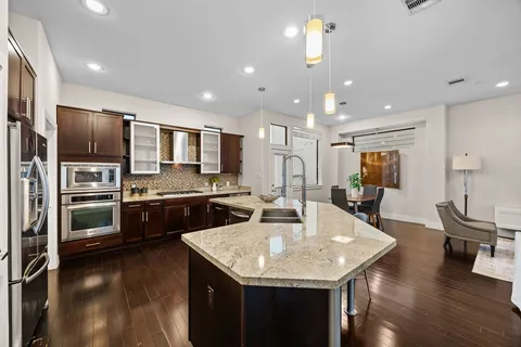 a kitchen with a center island appliances and wooden floor