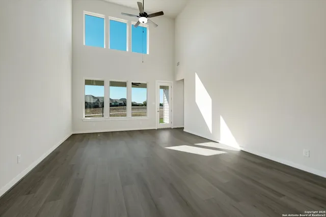 an empty room with wooden floor cabinet and windows