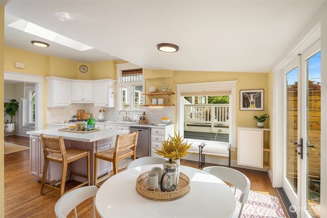 a kitchen with stainless steel appliances a dining table and chairs with wooden floor