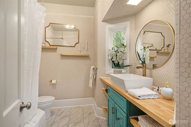 a bathroom with a granite countertop sink a toilet a mirror and vanity