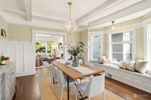 a dining room with wooden floor a chandelier a wooden table and chairs