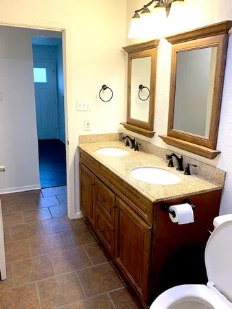 a bathroom with a granite countertop sink a mirror and a toilet