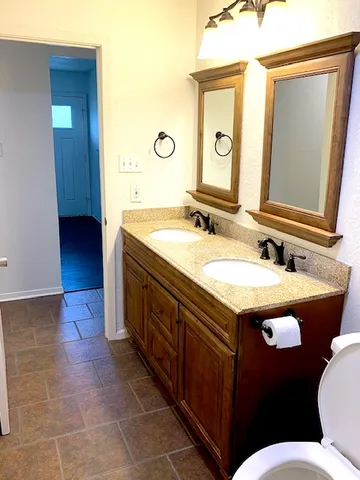 a bathroom with a granite countertop sink a mirror and a toilet
