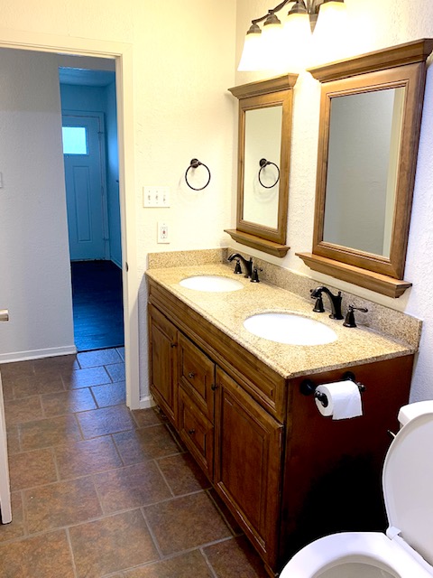 6114 Hogan Avenue Austin, TX 78741 - Photo 11 of 16 a bathroom with a granite countertop sink a mirror and a toilet