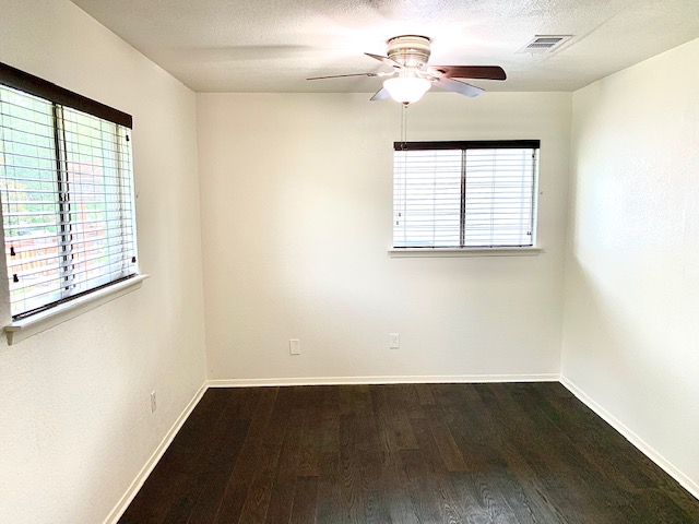 6114 Hogan Avenue Austin, TX 78741 - Photo 12 of 16 an empty room with wooden floor chandelier fan and windows