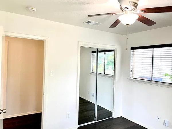 a view of an empty room with window and a ceiling fan