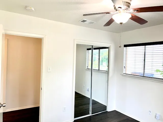 a view of an empty room with window and a ceiling fan