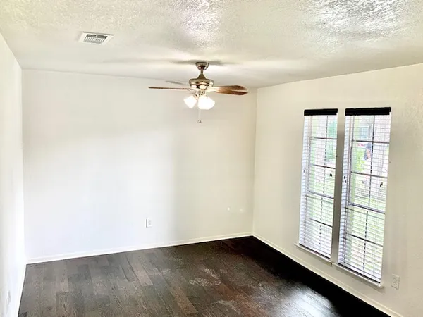 an empty room with windows and ceiling fan