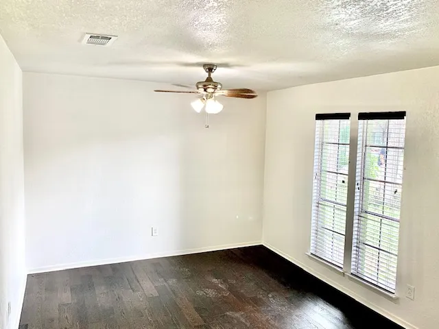 an empty room with windows and ceiling fan