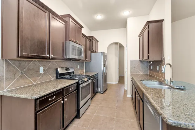 a kitchen with stainless steel appliances granite countertop a sink stove and refrigerator