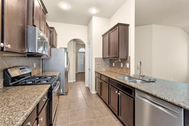a kitchen with stainless steel appliances granite countertop a sink stove and refrigerator