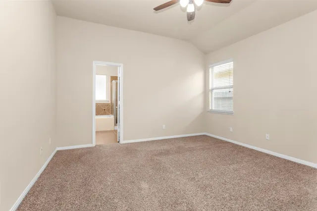an empty room with chandelier fan and windows