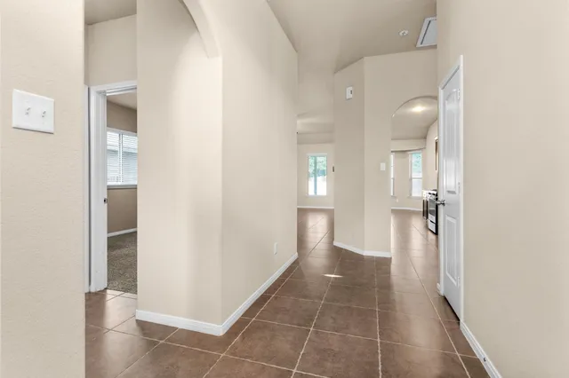 a view of a hallway with wooden floor and a bathroom