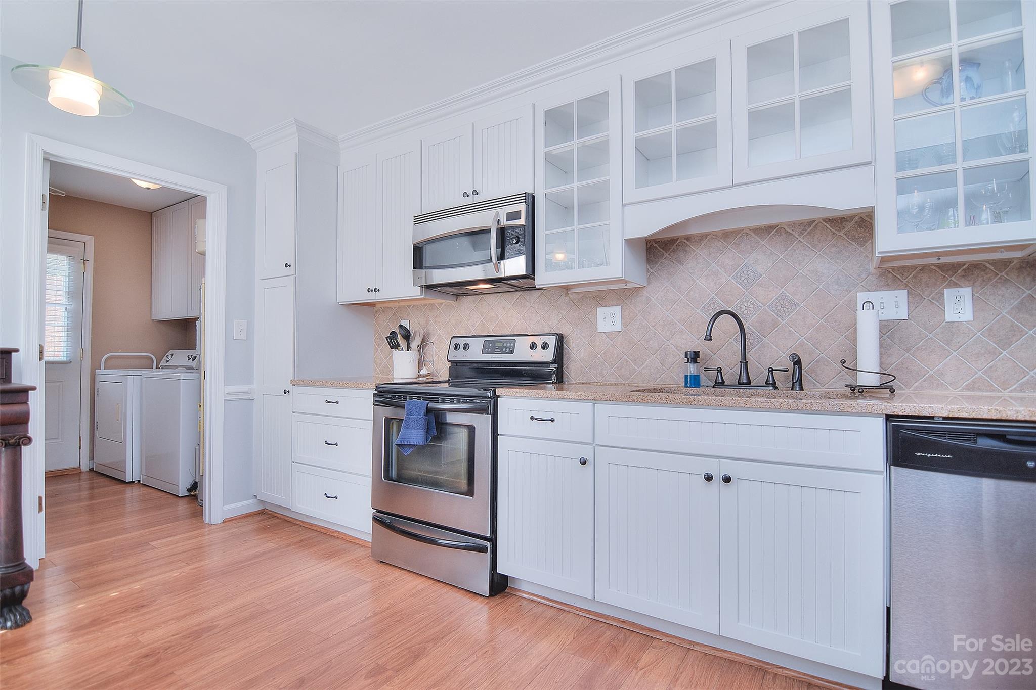 4415 Simsbury Road Charlotte, NC 28226 - Photo 12 of 36 a kitchen with stainless steel appliances granite countertop a sink cabinets and wooden floor