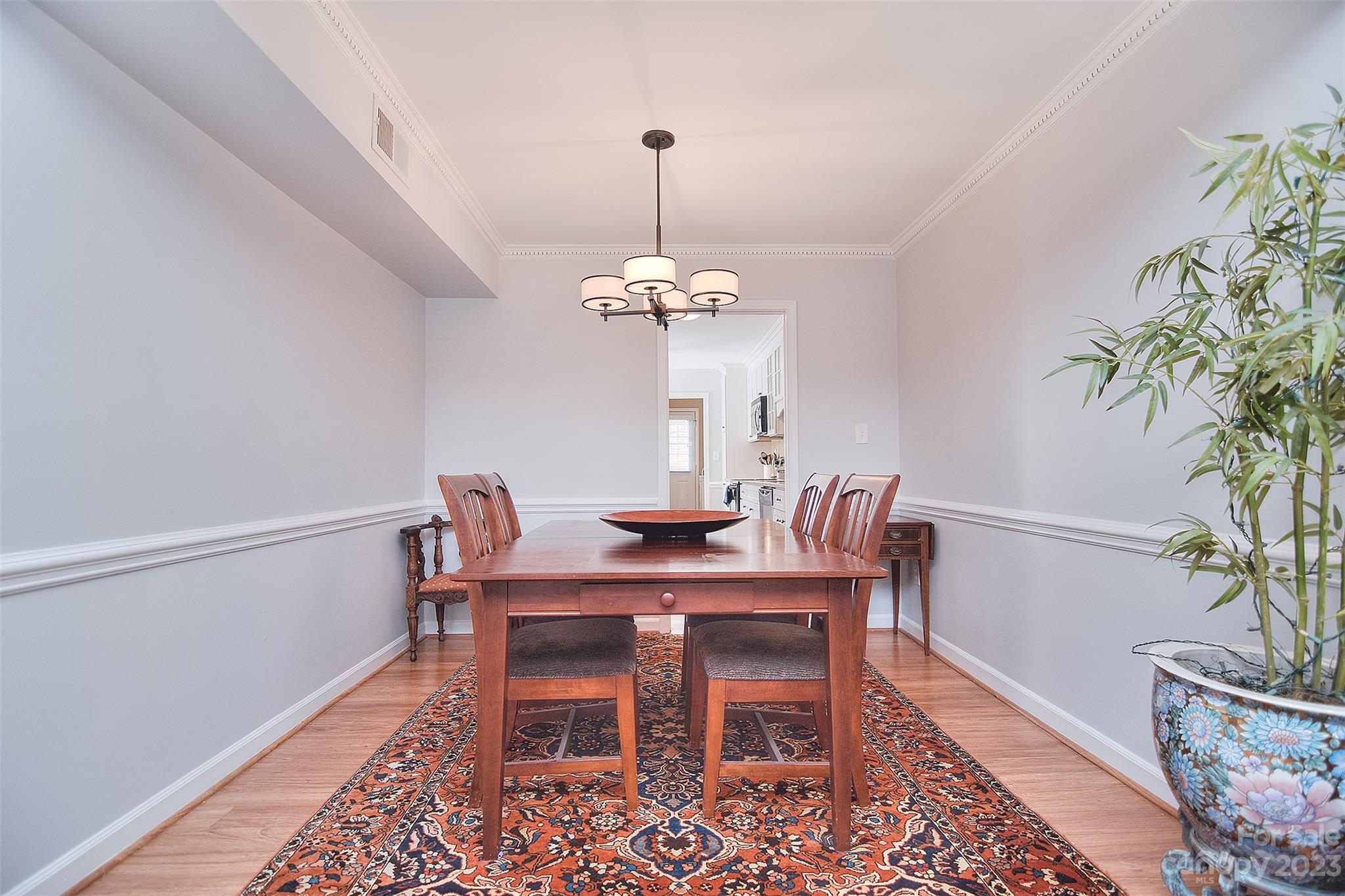 4415 Simsbury Road Charlotte, NC 28226 - Photo 9 of 36 a dining room with furniture potted plants a chandelier and wooden floor