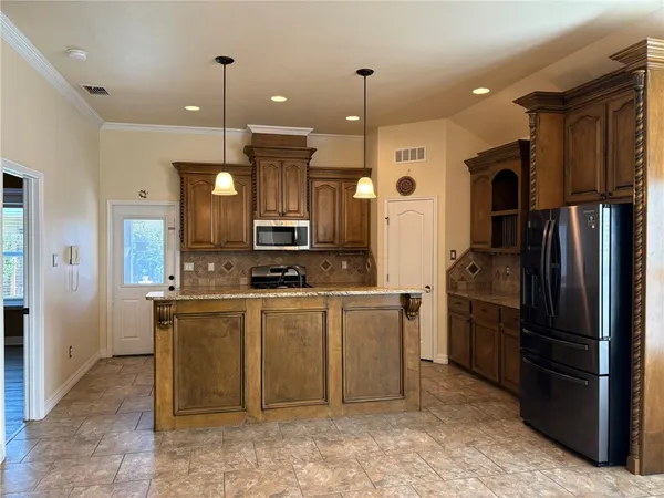 a large kitchen with stainless steel appliances kitchen island granite countertop a refrigerator and a sink