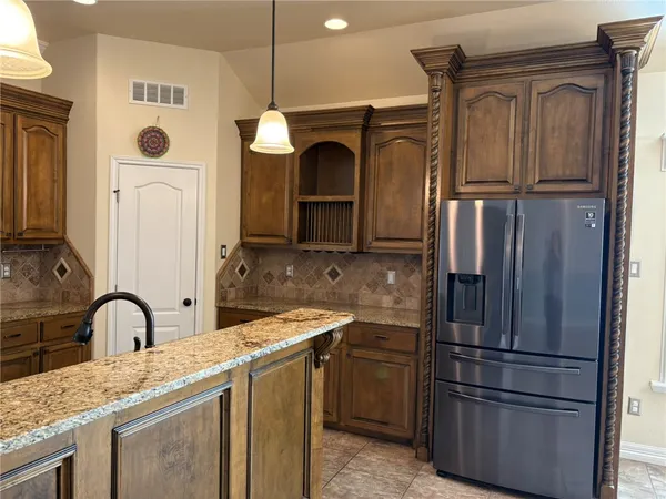 a kitchen with stainless steel appliances granite countertop a refrigerator a stove and a sink with wooden floor