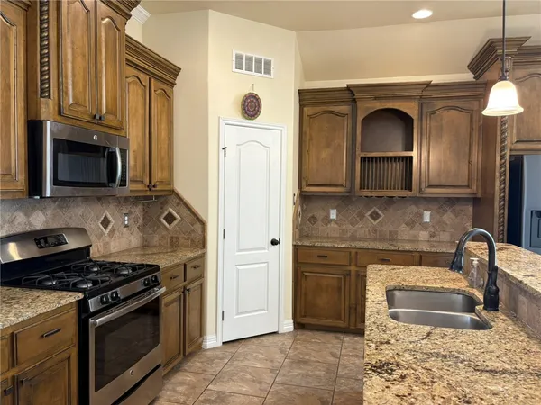 a kitchen with stainless steel appliances granite countertop a stove a sink and a microwave