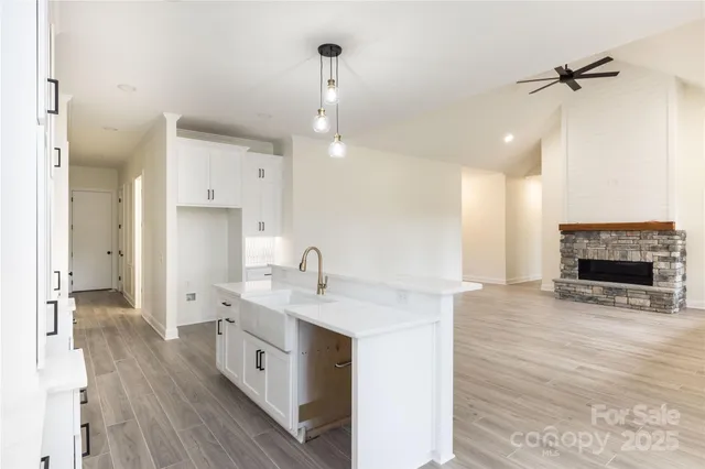 a large kitchen with a sink a counter top space stainless steel appliances and a fireplace