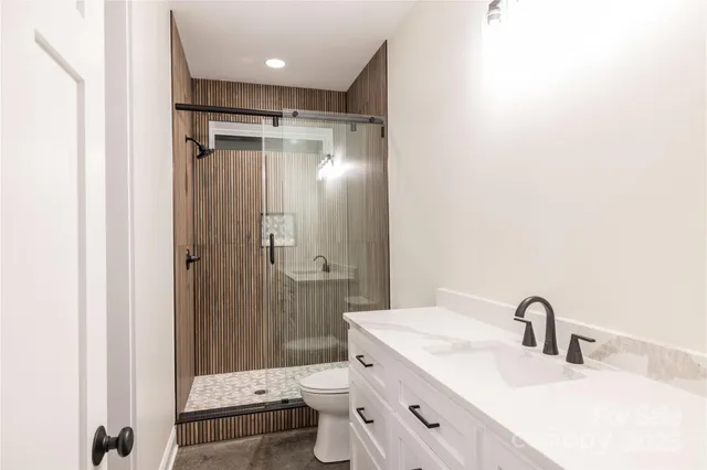 a bathroom with a shower sink vanity mirror and toilet