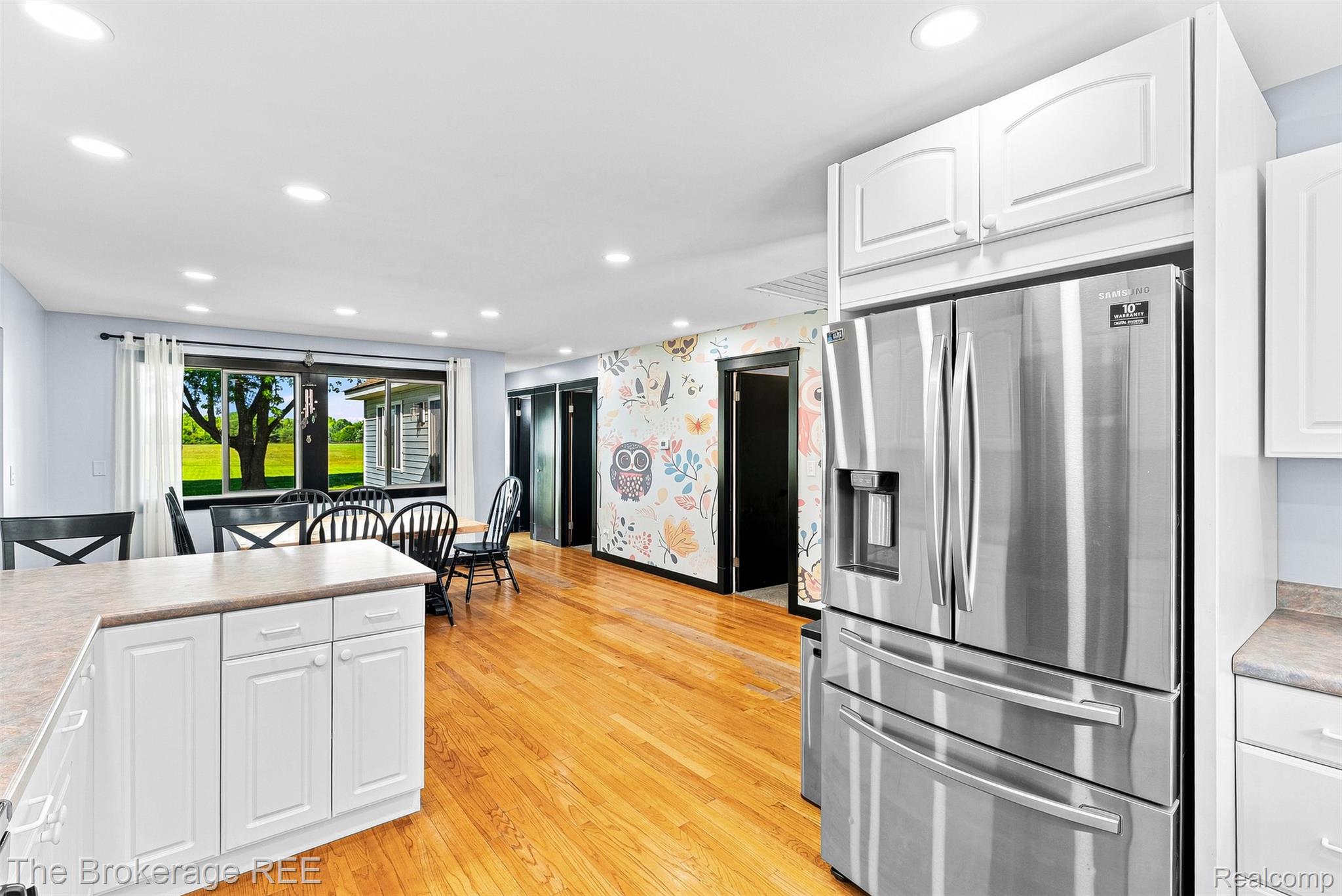 4443 North Gale Road Davison, MI 48423 - Photo 18 of 36 Chef's kitchen featuring stainless steel French-door refrigerator with dual drawers, white cabinetry with recessed panel doors, wood-finish flooring throughout, recessed ceiling lighting, and sliding glass doors opening to outdoor space