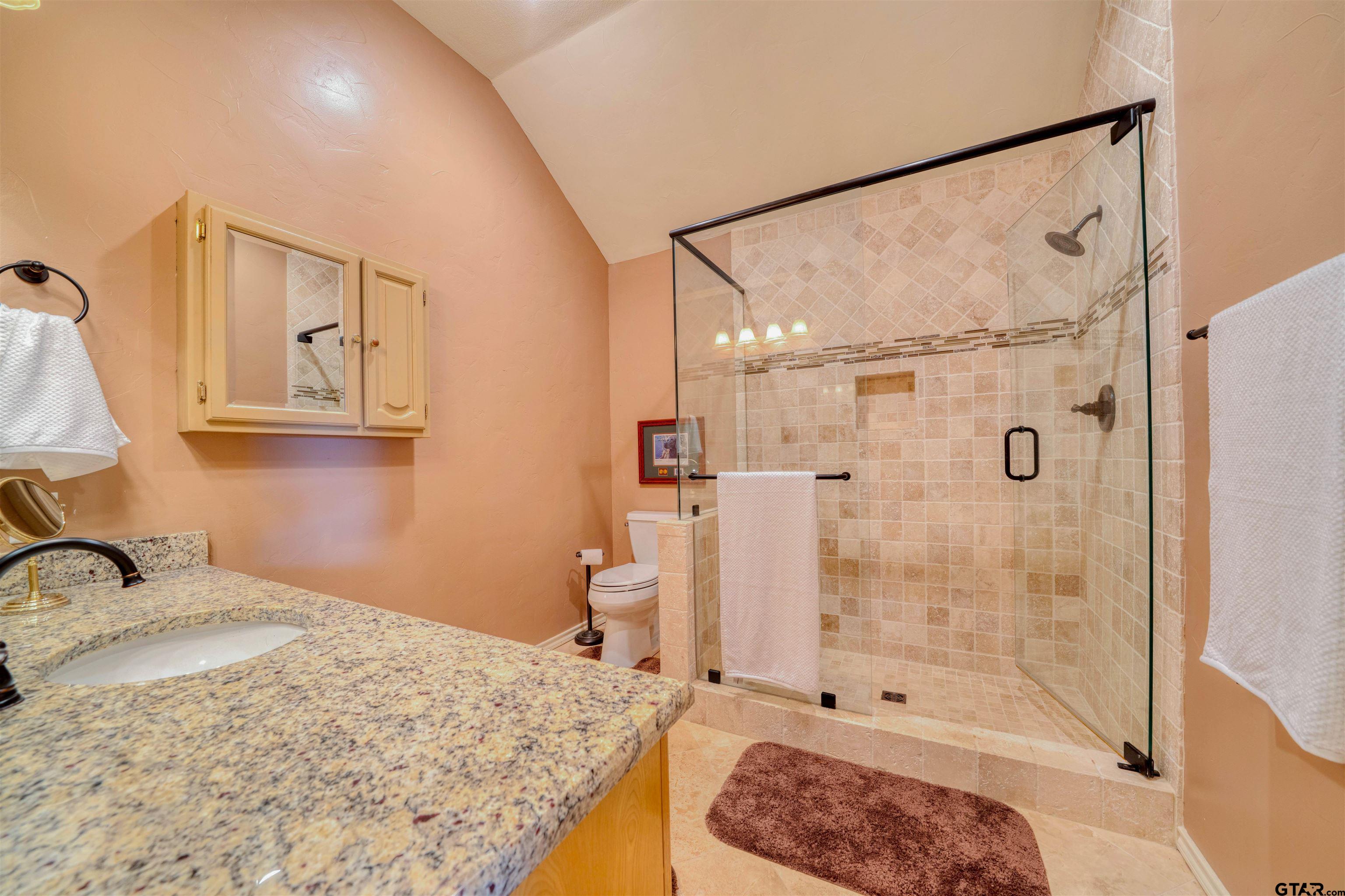 144 King Lyle Road Scroggins, TX 75480 - Photo 36 of 48 a bathroom with a granite countertop sink a mirror a shower and a bathtub