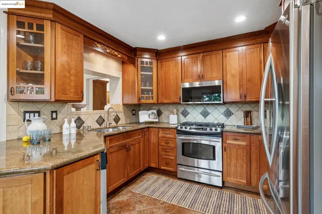 a kitchen with stainless steel appliances granite countertop a stove a sink and a microwave