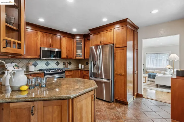 a kitchen with stainless steel appliances granite countertop a refrigerator a stove a sink a dining table and chairs