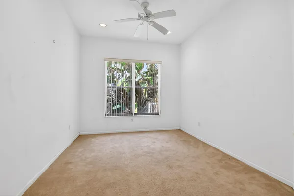 an empty room with a window and ceiling fan
