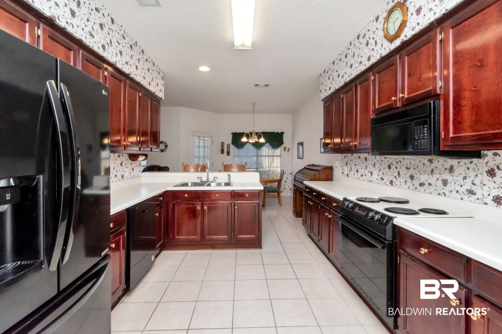 1032 Cross Gates Place Mobile, AL 36609 - Photo 14 of 34 Kitchen featuring black appliances, suspended lighting, reddish brown cabinets, light countertops, and light tile patterned flooring