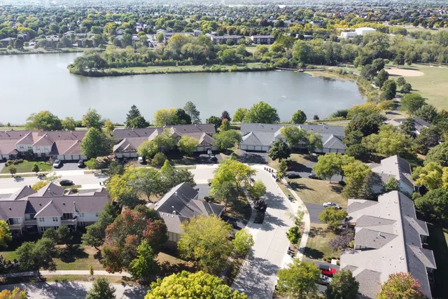 an aerial view of city and lake with trees all around