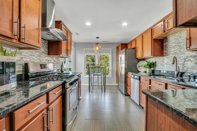 a kitchen with stainless steel appliances granite countertop lots of counter top space a stove a sink and a refrigerator