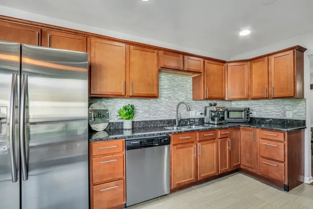a kitchen with stainless steel appliances granite countertop a sink a stove and a refrigerator