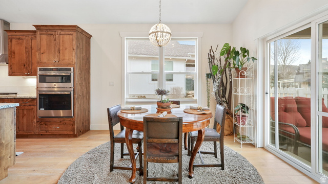 1238 Canyon View Road Midway, UT 84049 - Photo 11 of 36 Open-concept dining area featuring light wood-finish flooring, a contemporary chandelier, a large window, and a sliding glass door
