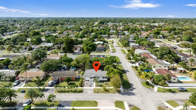 an aerial view of residential house with outdoor space and trees all around