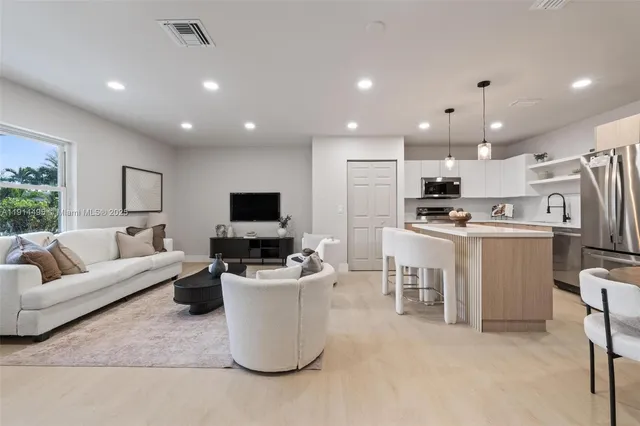 a living room with furniture a flat screen tv and kitchen view