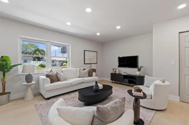 a living room with furniture a flat screen tv and a large window