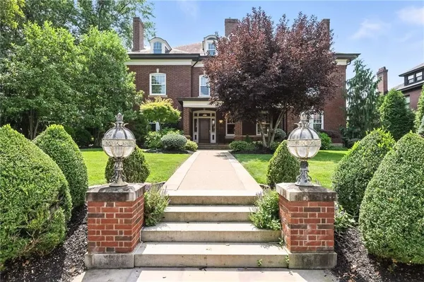 a front view of a house with garden and trees