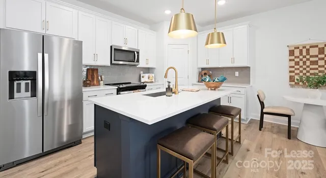 a kitchen with a sink a refrigerator and chairs