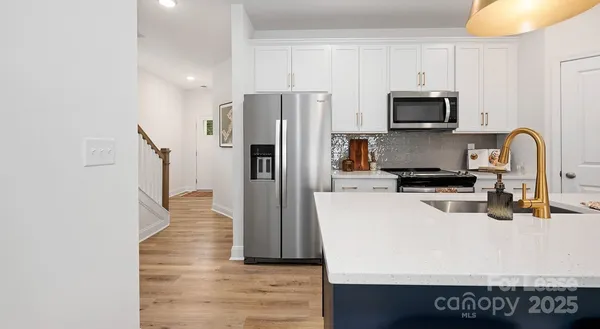 a kitchen with stainless steel appliances a refrigerator a stove a sink and white cabinets