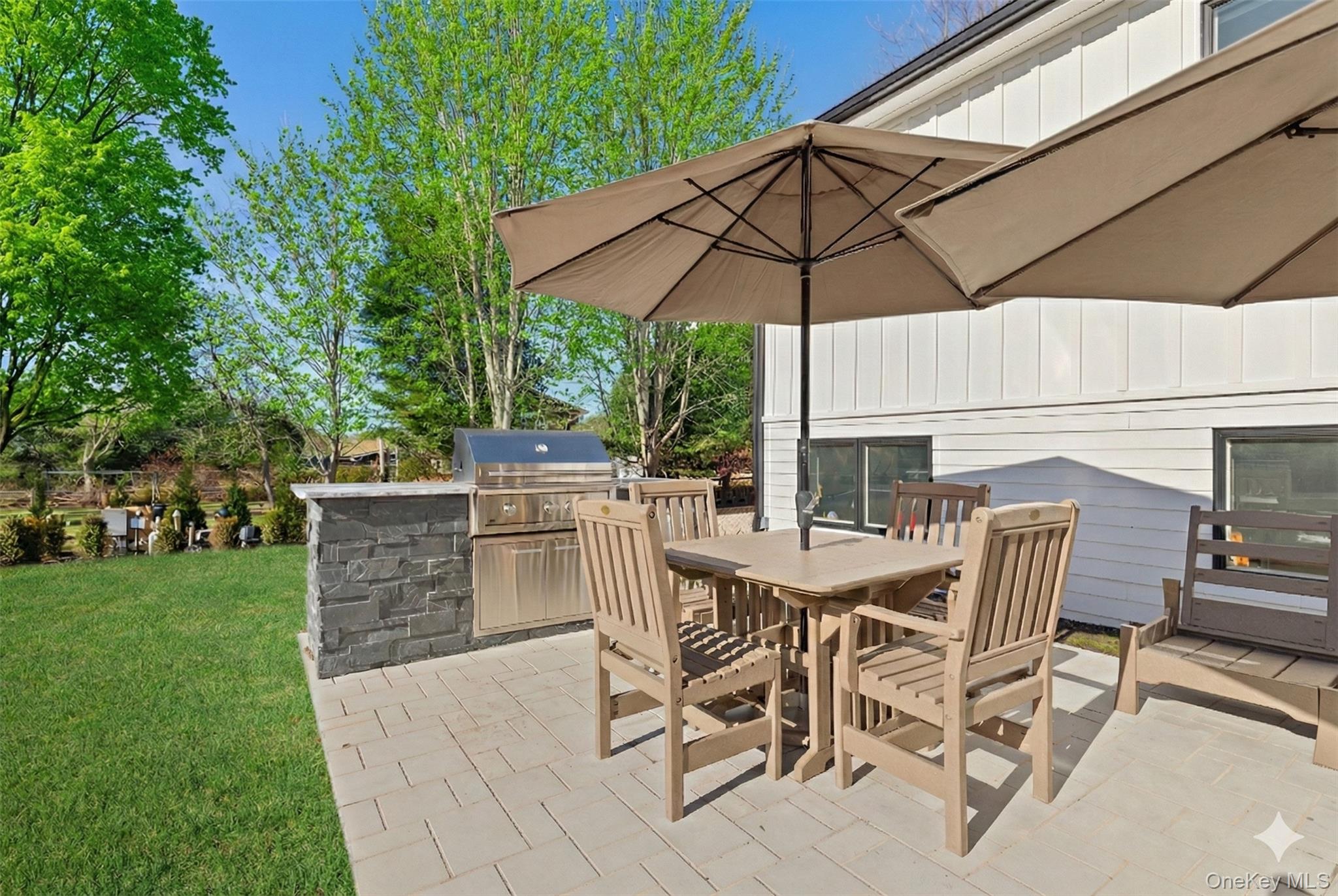 238 Sebonac Road Southampton, NY 11968 - Photo 21 of 23 a view of a dining table and chairs under an umbrella