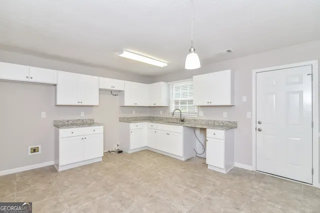 a kitchen with white cabinets and sink