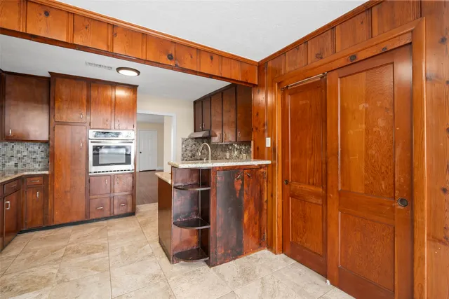 a room with stainless steel appliances kitchen island granite countertop a refrigerator and a sink