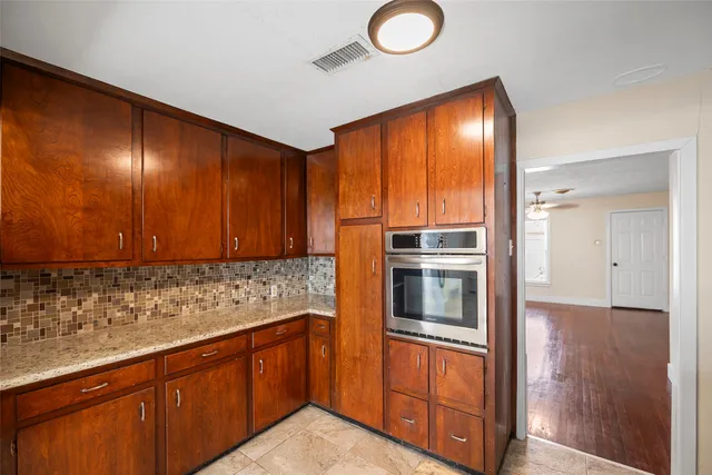 a kitchen with stainless steel appliances granite countertop a refrigerator a stove and a sink with wooden cabinets
