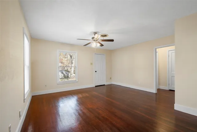 an empty room with wooden floor and windows