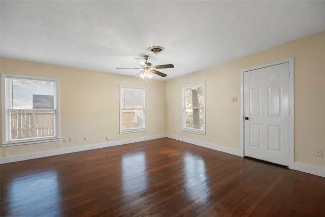 a view of an empty room with a window and wooden floor