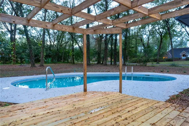 a view of a backyard with large trees and wooden fence