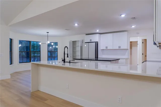 a large kitchen with stainless steel appliances a large counter top a stove and a refrigerator